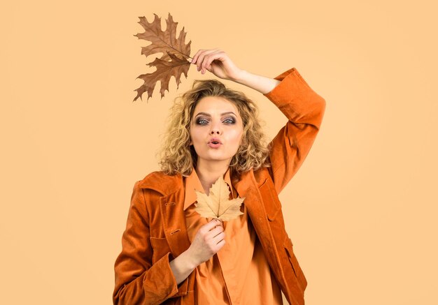 Modello di moda donna perfetta con foglie autunnali donna alla moda in giacca arancione con quercia gialla