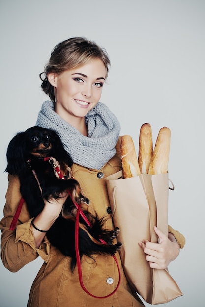 Modello di moda giovane donna. Ragazza, cane e baguette