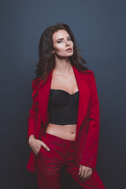 Modello di moda in abito rosso. Giovane donna in posa con abito rosso su grigio