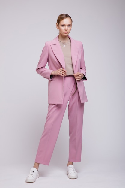 Modello di moda in rosa oversize giacca pantaloni sneakers sfondo bianco Studio Shot