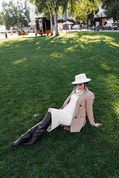 Modello di moda indossato bianco in posa sull'erba. Ritratto di stile di vita.