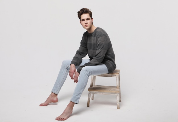 Modello di moda uomo alla moda seduto sulla sedia