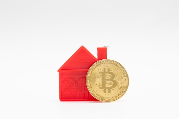 Modello di piccola casa rossa modello e moneta bitcoin oro su bianco