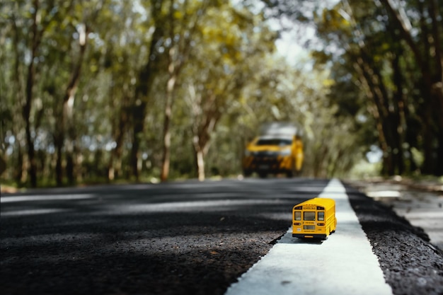 Modello di scuolabus giallo giocattolo su strada di campagna Ritorno a scuolaIl concetto di istruzione sullo sfondo
