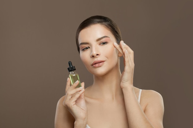 Modello di spa per donne sane con olio cosmetico su sfondo marrone concetto di cura del viso e del corpo