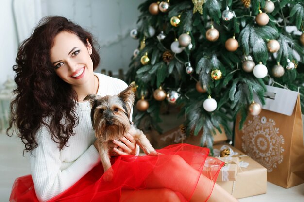 Modello donna in un abito rosso in uno studio fotografico con in mano un regalo di Capodanno.