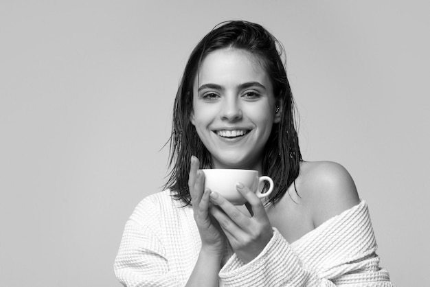 Modello femminile che tiene tazza di caffè Donna sorridente felice in accappatoio con studio di tazza di caffè isolato