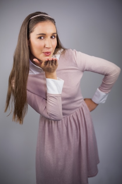 Modello grazioso rilassato con vestito rosa sul baciare alla macchina fotografica