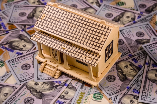 Modello in compensato della casa e banconote da cento dollari Concetto di prestito immobiliare