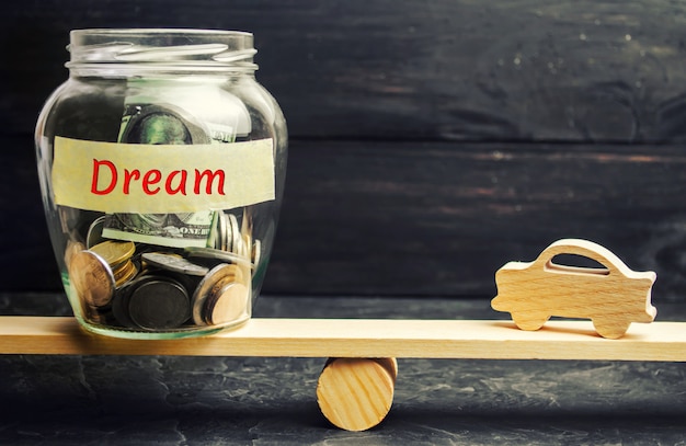 Modello in legno della macchina e un vaso di vetro con monete e la scritta Dream