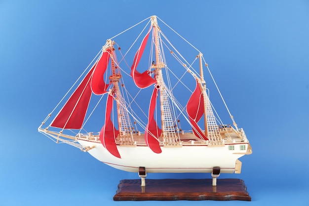 Modello in miniatura di vecchia nave con vele rosse su sfondo blu