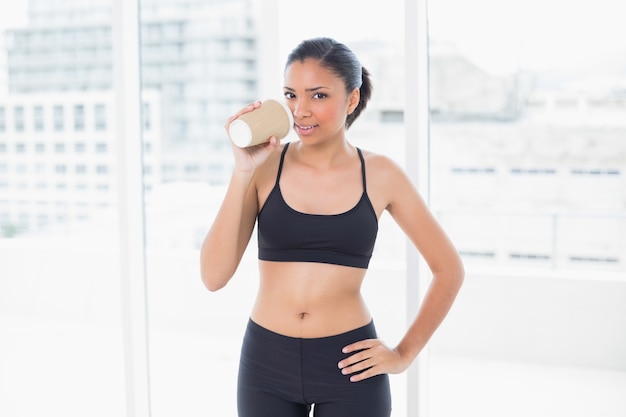 Modello ponderoso dai capelli scuri in sportswear bere caffè