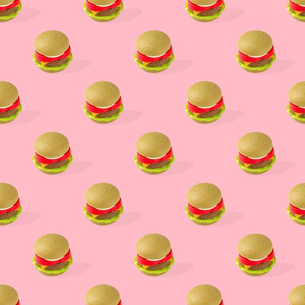 Modello senza cuciture degli alimenti a rapida preparazione dell'hamburger del giocattolo su fondo rosa. Malsano. Non biologico