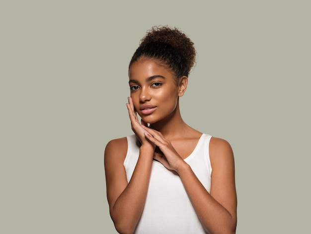 Modello sorridente del viso della pelle nera della donna di bellezza che tocca il suo fronte. Colore di sfondo. Verde