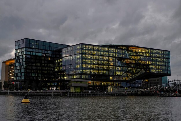 Modern illuminated building amsterdam night cityscape from canals netherlands