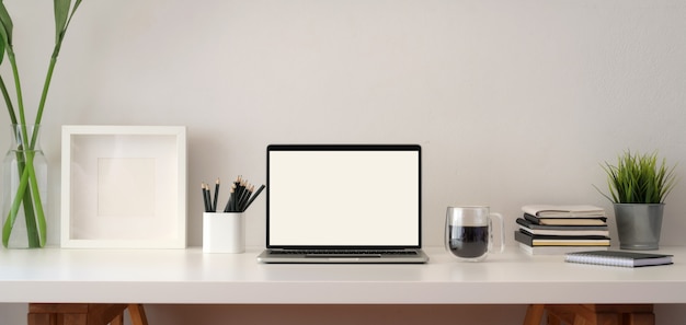 Modern office room with blank screen laptop computer with frame and office supplies