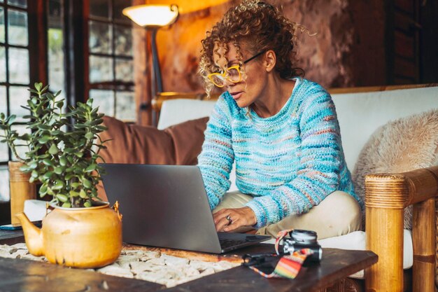 Moderna donna carina adulto di mezza età che lavora a casa con il computer portatile seduto sul couchactivity