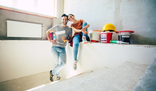 Moderna giovane coppia felice innamorata in abiti casual durante la nuova riparazione domestica o il rinnovamento delle pareti con molti strumenti per questo