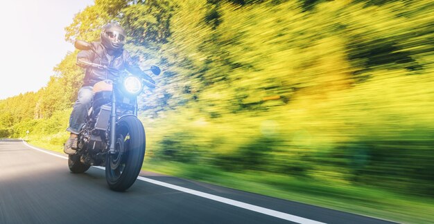 Moderna moto scrambler sulla strada forestale in sella divertendosi a guidare la strada vuota in un viaggio in motocicletta Copyspace per foto con sfocatura in movimento dinamico reale per il tuo testo individuale