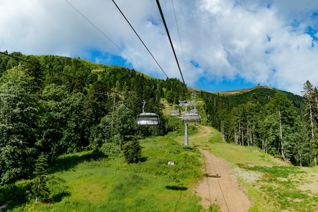 Moderne funivie o funivie con persone contro il cielo blu della valle verde e le cime delle montagne