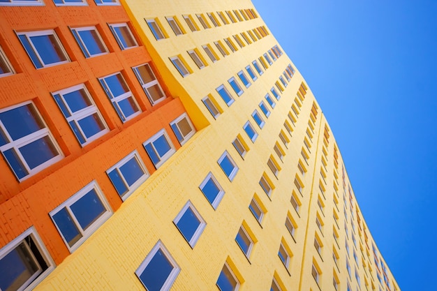 Moderno edificio a più piani con molte finestre di vetro sullo sfondo del cielo azzurro e del sole. Edifici residenziali, foto stock di immobili urbani