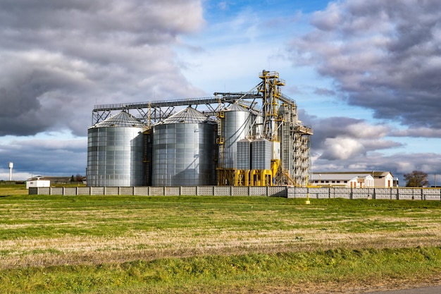 Moderno elevatore per granaio e linea di pulizia delle sementi in silos d'argento su impianto di agroprocessing e produzione per lo stoccaggio e la lavorazione essiccazione pulitura di prodotti agricoli farina cereali e grano