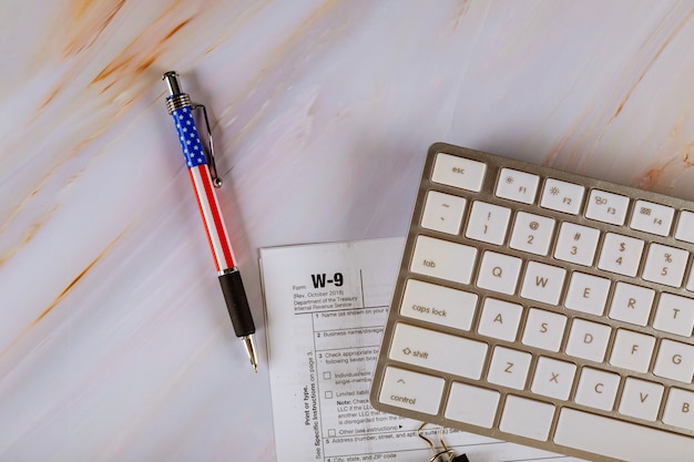 Modulo fiscale federale W-9 USA per le finanze aziendali dell'Internal Revenue Service con penna, tastiera del computer