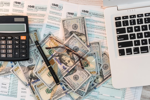 Modulo fiscale USA 1040 con penna, dollaro e laptop in ufficio. tempo fiscale. concetto di contabilità.