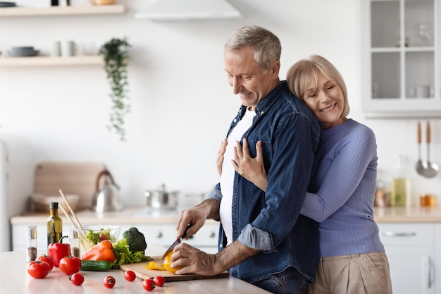 Moglie felice che abbraccia il marito che cucina la cena