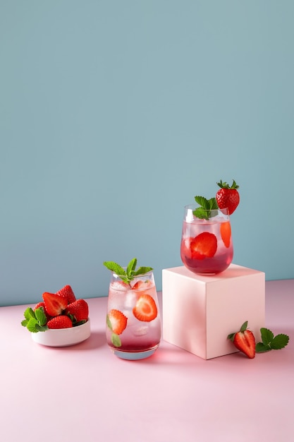 Mojito alla fragola su sfondo blu e podio rosa. Bevanda estiva rinfrescante con copia spazio