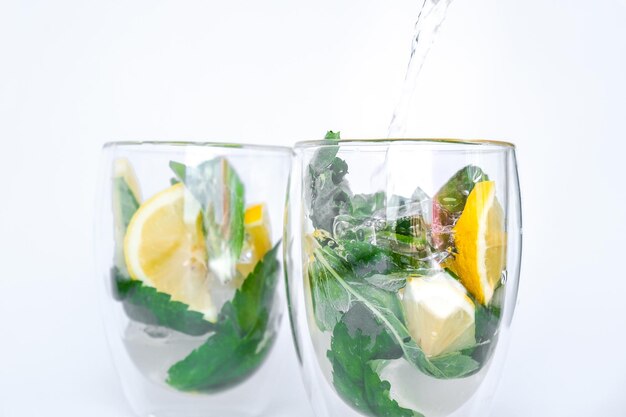 Mojito cocktail rinfrescante versando bevande alcoliche limonata con foglie di limone e menta alla luce