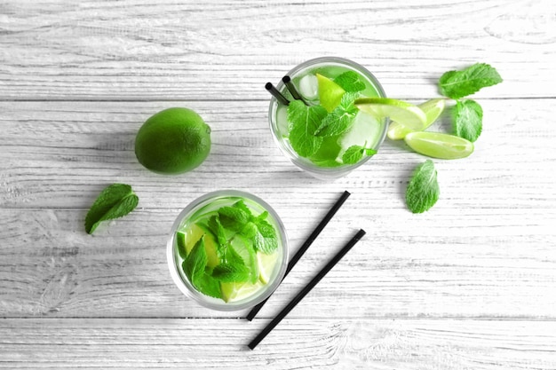 Mojito fresco freddo con fette di menta e lime in bicchieri su sfondo di legno