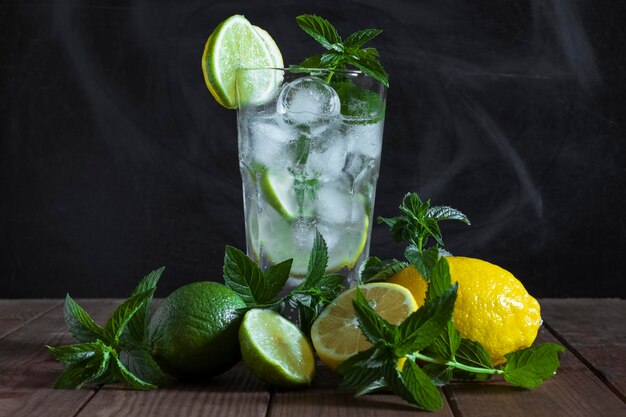 Mojito in vetro trasparente con frutta ghiacciata e menta su sfondo scuro