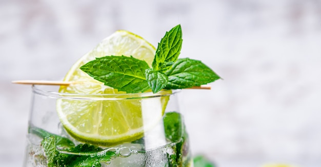 Mojito rinfrescante con lime, menta e ghiaccio in un bicchiere da vicino. Cocktail estivo freddo.