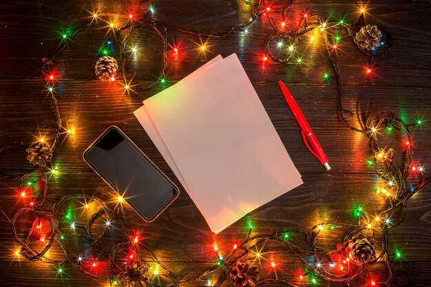 Mokcup di Capodanno e Natale. notebook con luci di Natale su sfondo di legno, spazio per il testo, copyspace. da sopra. Concetto di pianificazione delle vacanze invernali. Stile piatto.