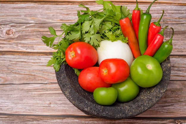 Molcajete con verdure su tavola di legno Ingredienti per una salsa piccante