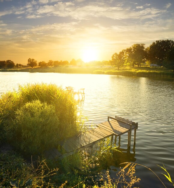 Molo da pesca in legno vicino al fiume all'alba