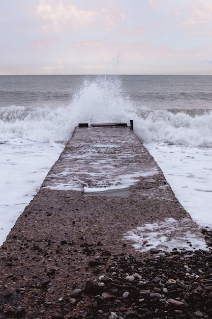 Molo di pietra sulla costa con onde e linea dell'orizzonte