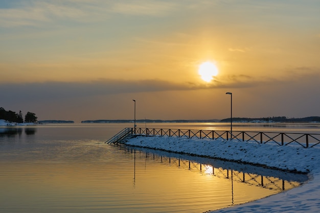 Molo innevato al tramonto in riva al mare