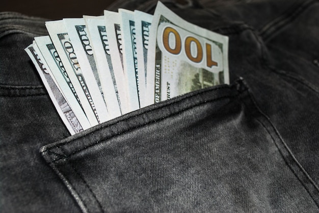 Molte banconote da cento dollari nella tasca dei jeans. I dollari americani sono visibili nella tua tasca.