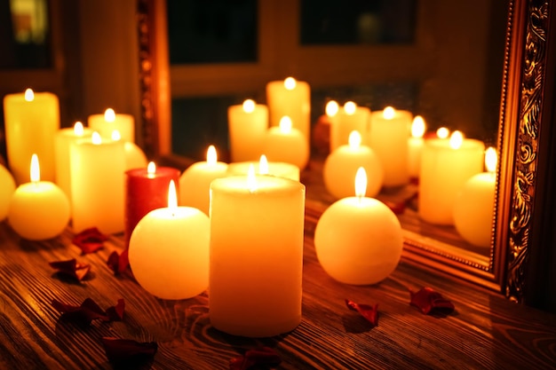 Molte candele accese riflesse nello specchio sul tavolo