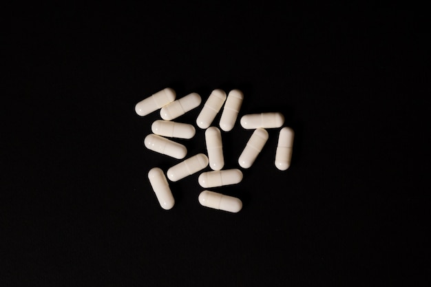 Molte capsule di pillole bianche lenitive, antivirali, vitamine su sfondo nero