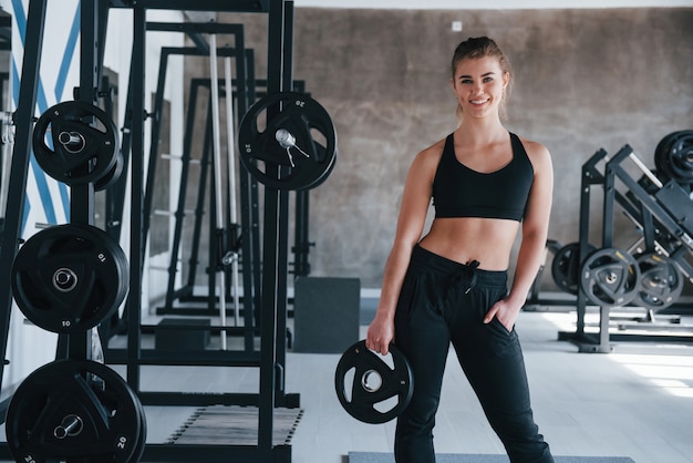 Molte delle attrezzature. splendida donna bionda in palestra durante il suo weekend