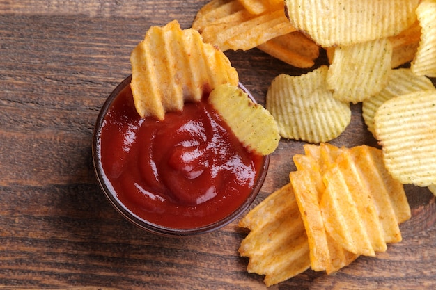 Molte diverse patatine fritte con salsa rossa su un tavolo di legno marrone