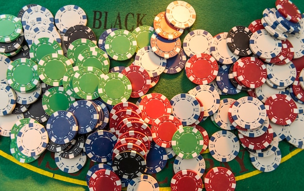 Molte fiches da poker di costo diverso sul tavolo da gioco. grande scommessa di gioco sul campo di stoffa verde, primo piano