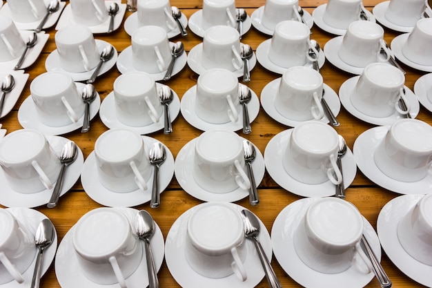 Molte file di tazza di caffè bianco e piattino per seminario