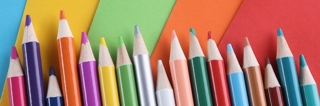 Molte matite colorate che si trovano su uno sfondo colorato luminoso