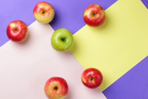 Molte mele su uno sfondo colorato Mele rosse e verdi sparse su una superficie colorata Frutta fresca per una dieta sana Vista dall'alto