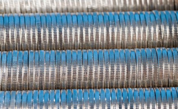 Molte monete metalliche rotonde di colore argento illuminate in blu