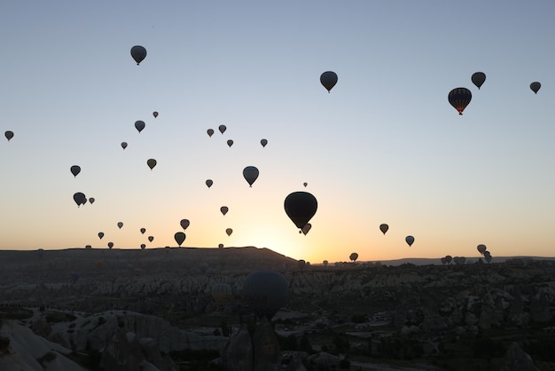 Molte mongolfiere che volano nel cielo al tramonto al parco nazionale di cappadocia turchia goreme al tramonto